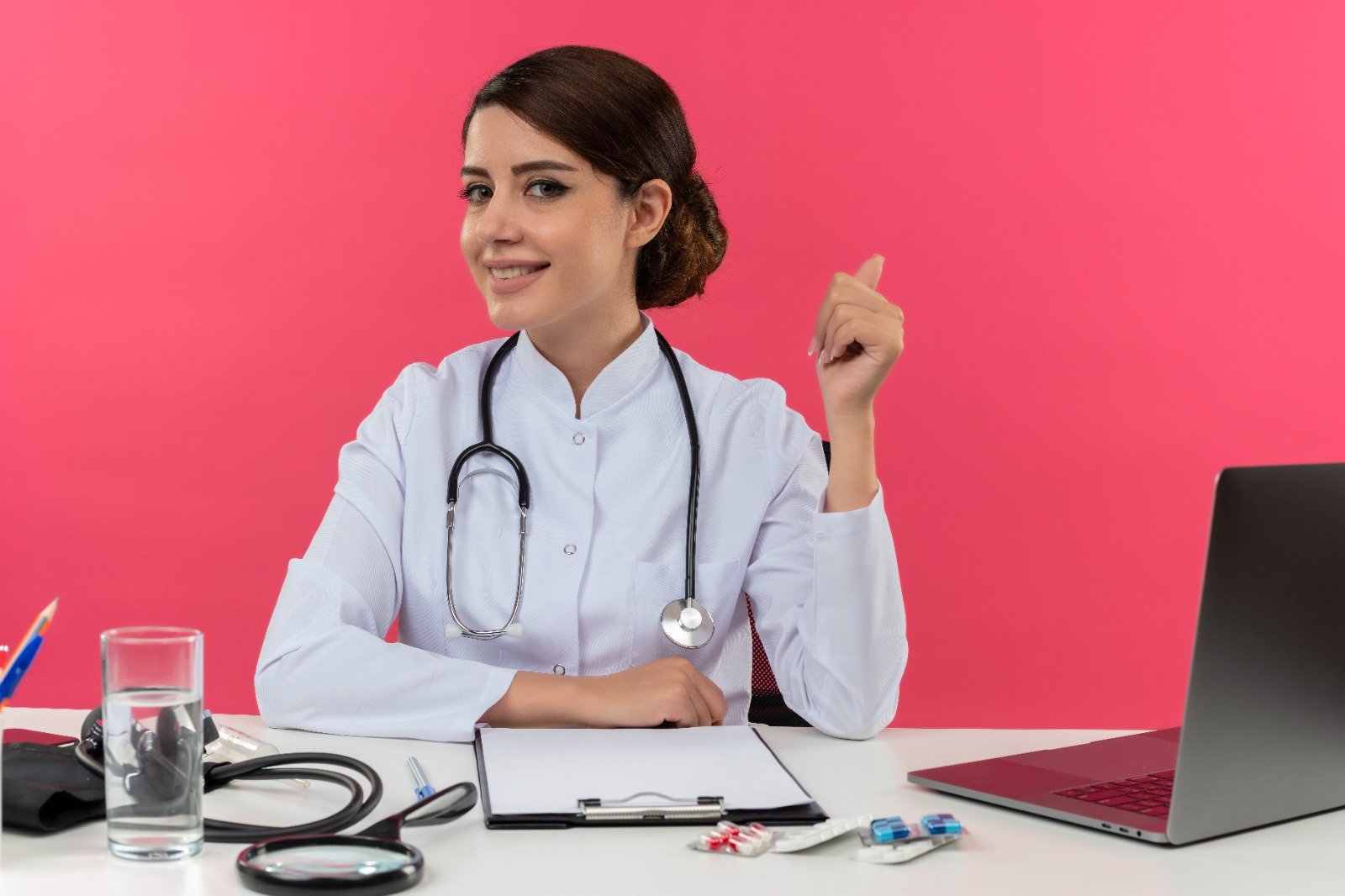 Doctor seated at a desk with a laptop and medical equipment