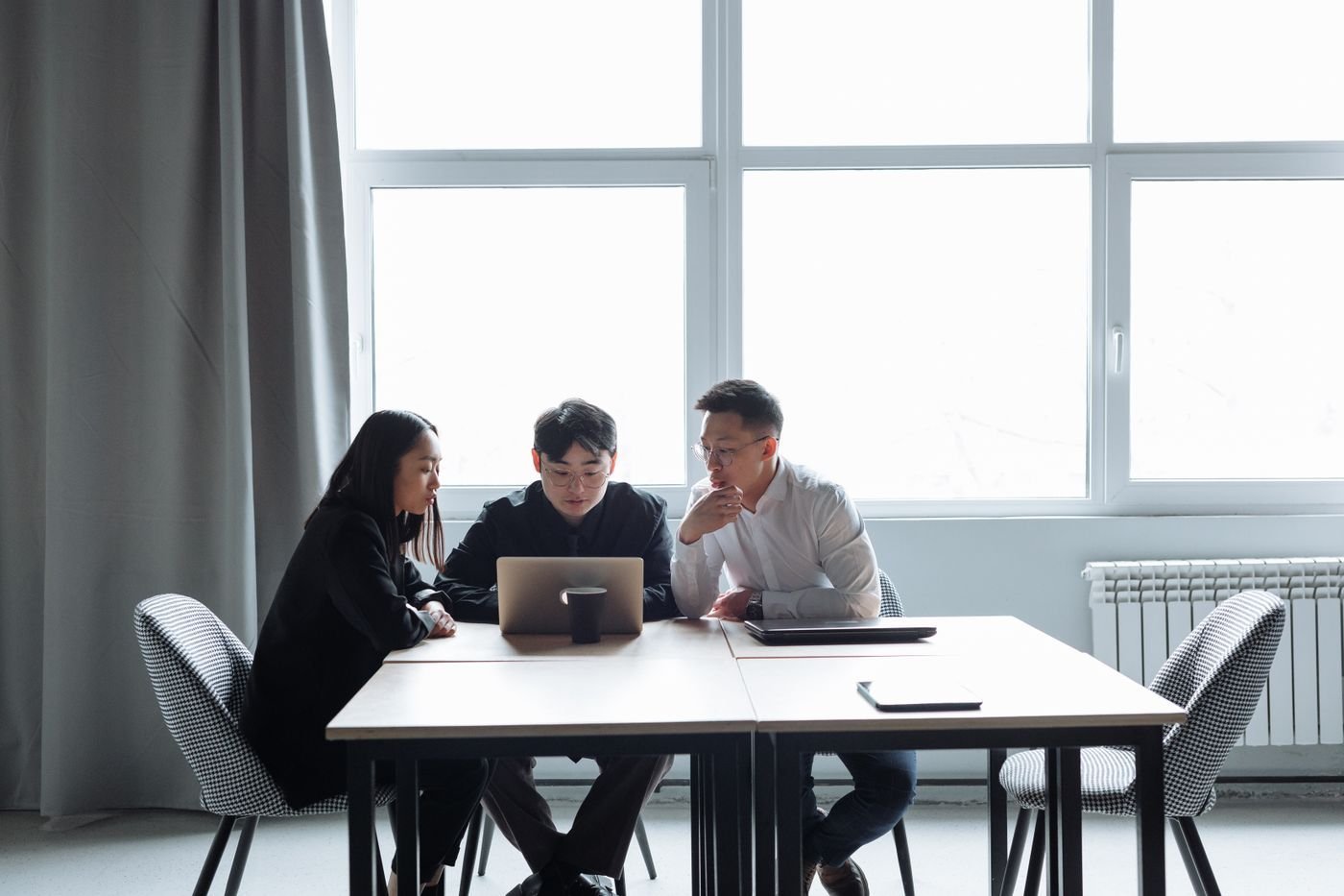 Colleagues discussing work around a laptop